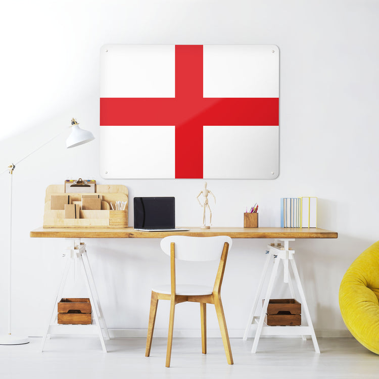 A desk in a workspace setting in a white interior with a magnetic metal wall art panel with an England flag design