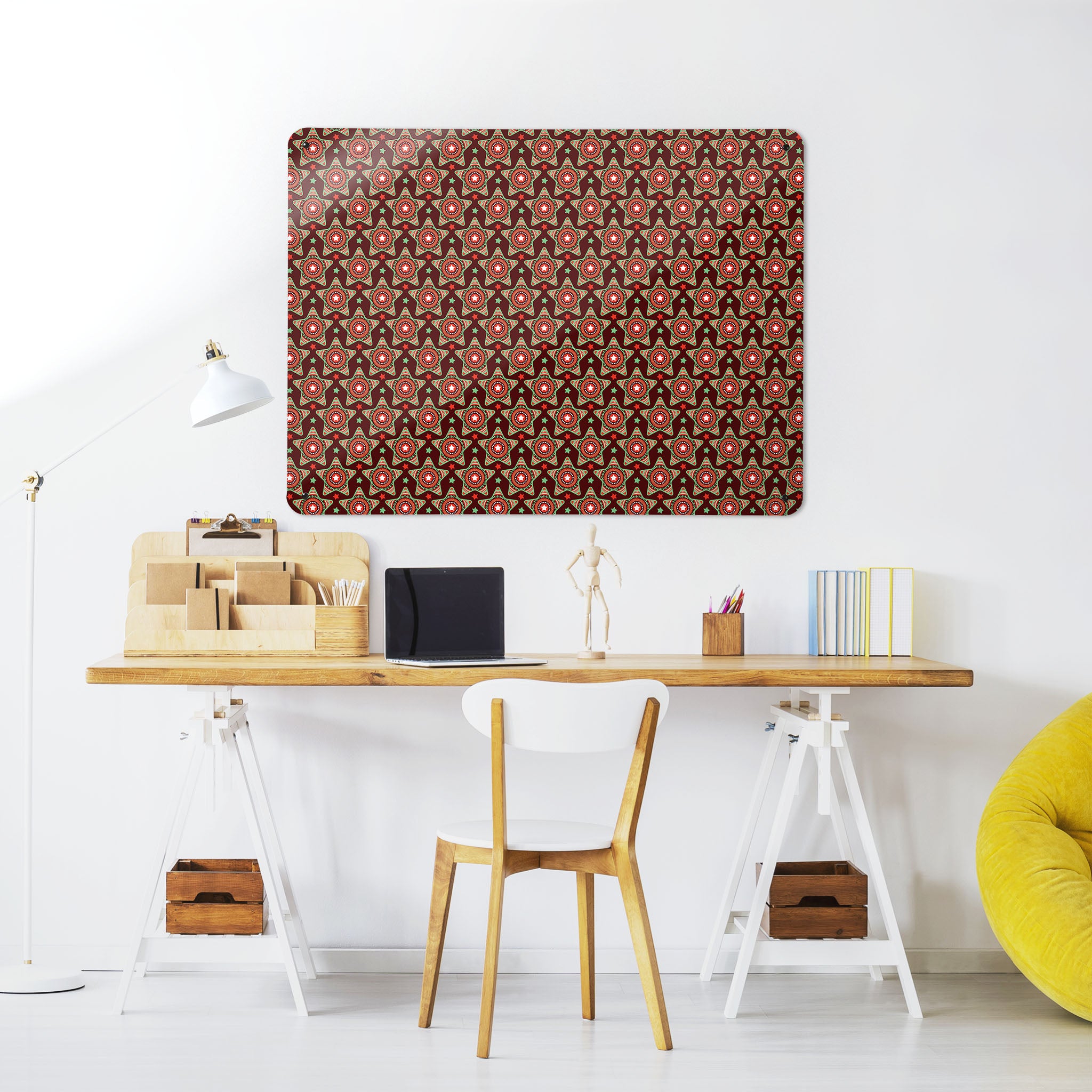 A desk in a workspace setting in a white interior with a magnetic metal wall art panel showing a stars on maroon repeat pattern design
