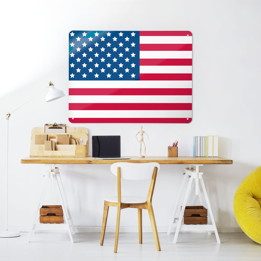 A desk in a workspace setting in a white interior with a magnetic metal wall art panel with a Stars and Stripes American Flag design