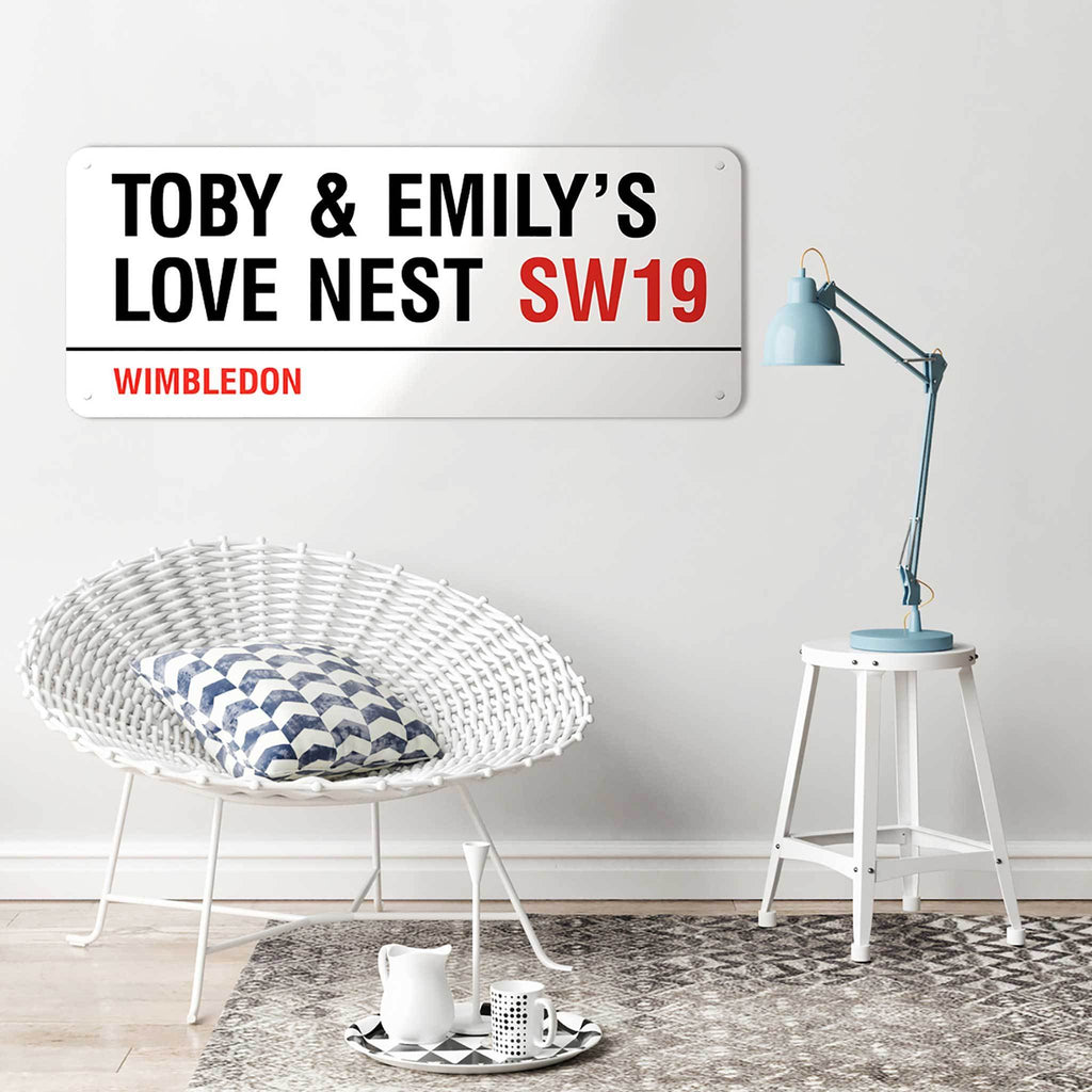 A personalised 100 cm London street sign reading Toby & Emily’s Love Nest SW19, Wimbledon, above a wicker chair