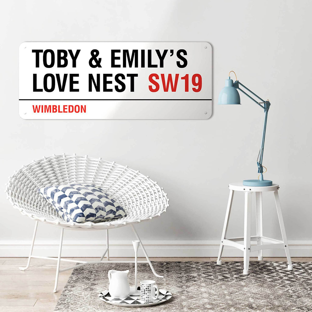 A personalised 100 cm London street sign reading Toby & Emily’s Love Nest SW19, Wimbledon, above a wicker chair