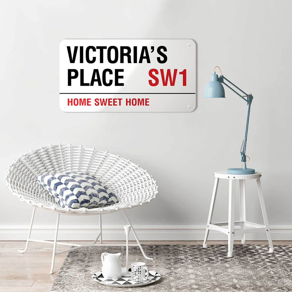 A personalised London street sign reading Victoria’s Place SW1, Home Sweet Home, above a wicker chair