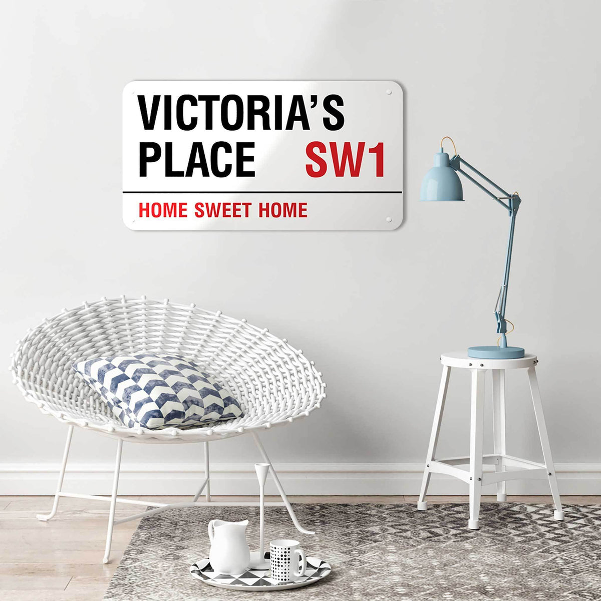 A personalised London street sign reading Victoria’s Place SW1, Home Sweet Home, above a wicker chair