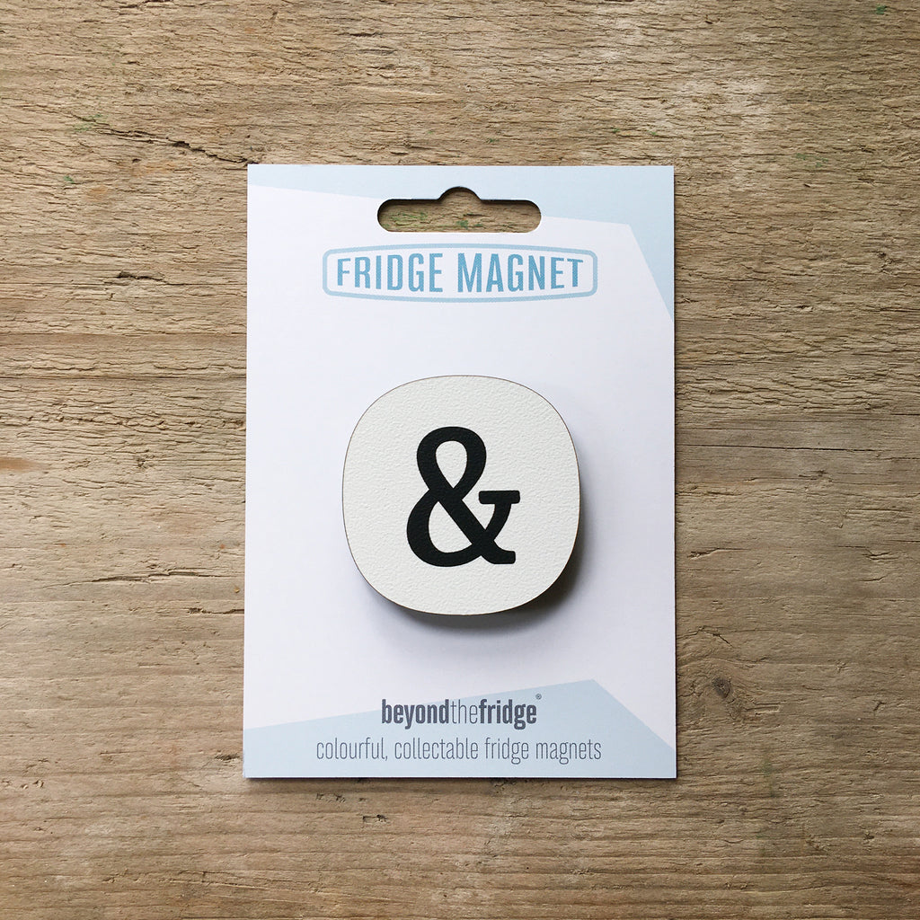 An ampersand fridge magnet in its Beyond the Fridge card packaging, on a wooden table