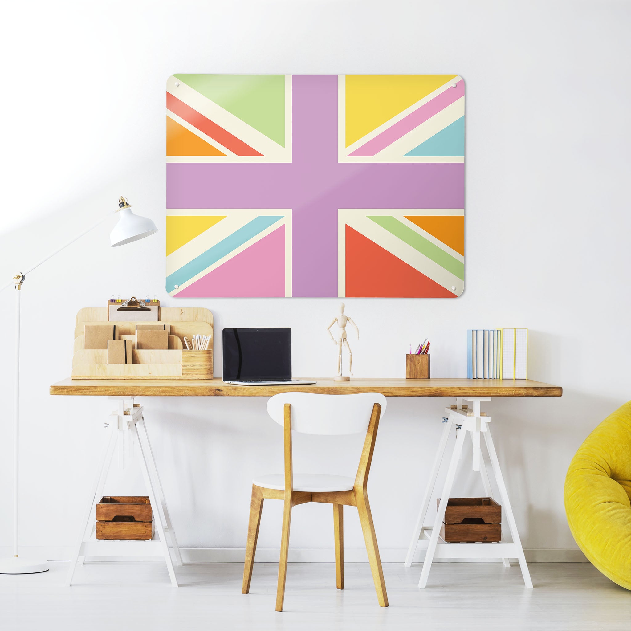 A desk in a workspace setting in a white interior with a magnetic metal wall art panel with a Union Jack design in multi colours