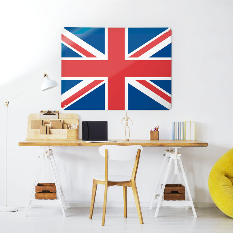 A desk in a workspace setting in a white interior with a magnetic metal wall art panel with a Union Jack design