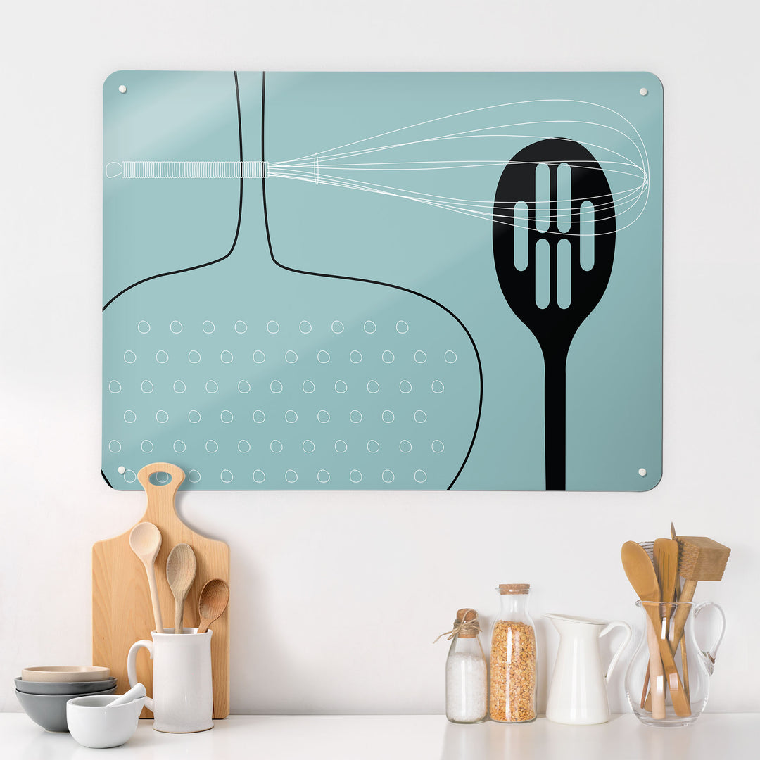 A kitchen interior with a magnetic metal wall art panel showing a blue utensils design 