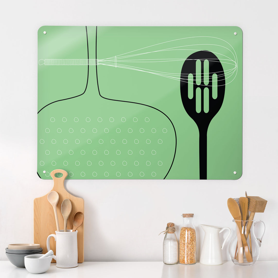 A kitchen interior with a magnetic metal wall art panel showing a green utensils design 