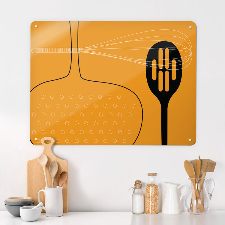 A kitchen interior with a magnetic metal wall art panel showing a orange utensils design 