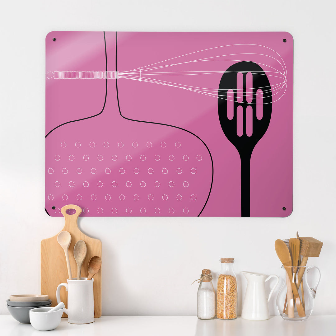 A kitchen interior with a magnetic metal wall art panel showing a pink utensils design 
