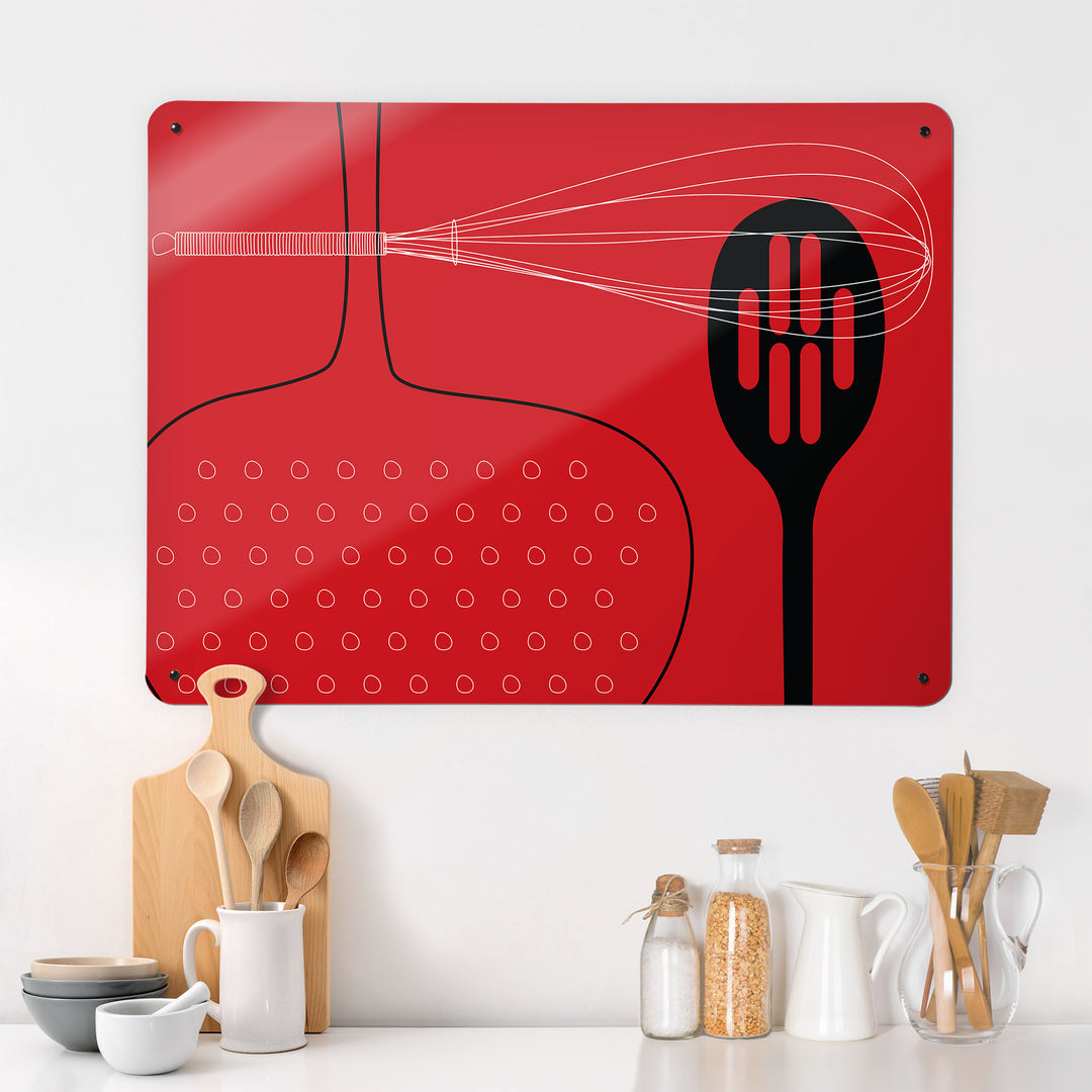A kitchen interior with a magnetic metal wall art panel showing a red utensils design 
