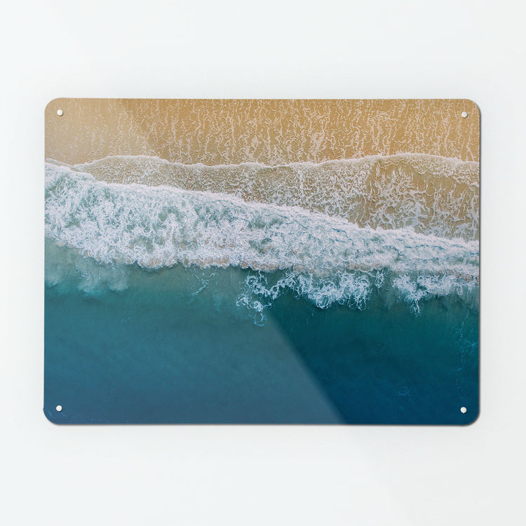 A large magnetic notice board by Beyond the Fridge with a bird's eye photograph of waves breaking on a sandy shore