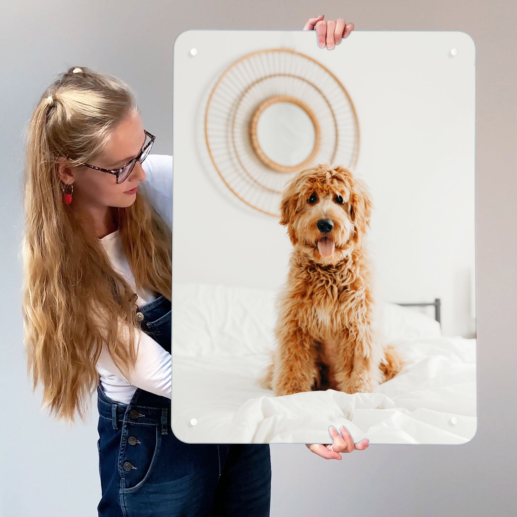A girl holding up a portrait Create Your Own board printed with a photograph of her dog