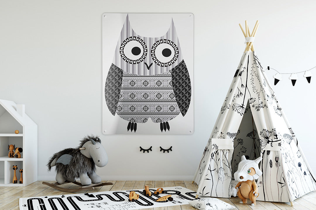 A magnetic board printed with a patterned grey owl on a child's bedroom wall, beside a play tepee and a rocking horse