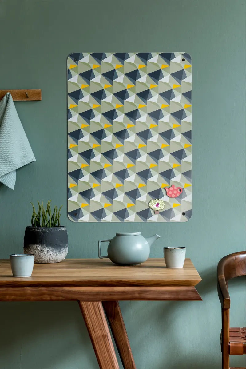 A Shards magnetic board in concrete and yellow above a wooden table with a teapot.