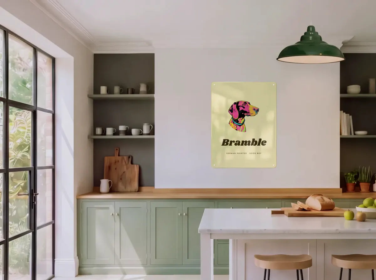 A pop art pet portrait board with the name Bramble on a kitchen wall between open shelves.
