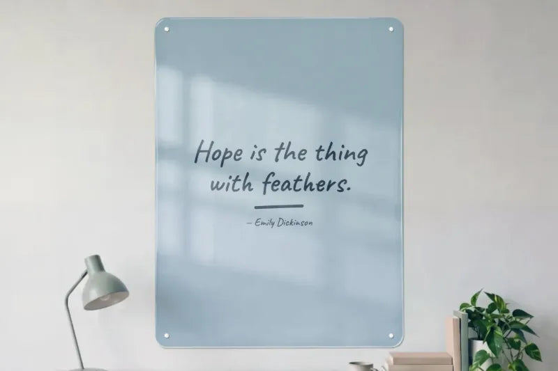 A dusty blue board above a desk: Hope is the thing with feathers. — Emily Dickinson.